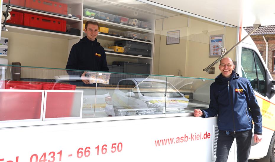 Constantin Knopf (links) und Wolfgang Mainz im und am neuen Verpflegungswagen des ASB Kiel.